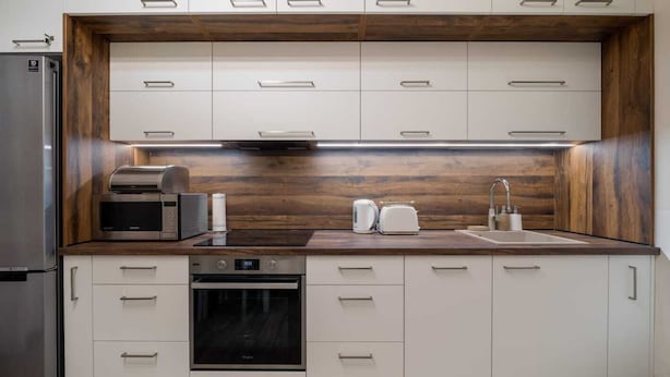 Una cucina moderna con mobili bianchi, forno integrato, microonde e tostapane.