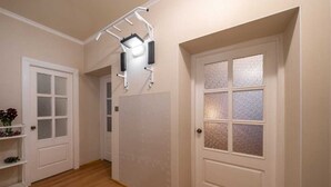 Un corridoio con pavimento in legno, porte bianche dotate di pannelli trasparenti satinati e una macchina per esercizi fissata al soffitto.