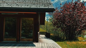 A wooden cabin with a deck, large windows, and a mountain backdrop. - Alpine Escape - Iconic Views & Timeless Design (Grindelwald)