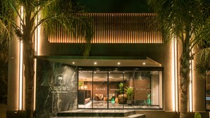 A modern boutique hotel entrance with a marble facade, glass doors, and a welcoming interior visible through the windows.