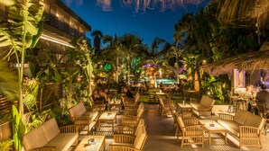 An outdoor dining area with wooden furniture and tropical plants.