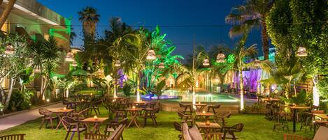 An outdoor patio area with wooden furniture and a pool.