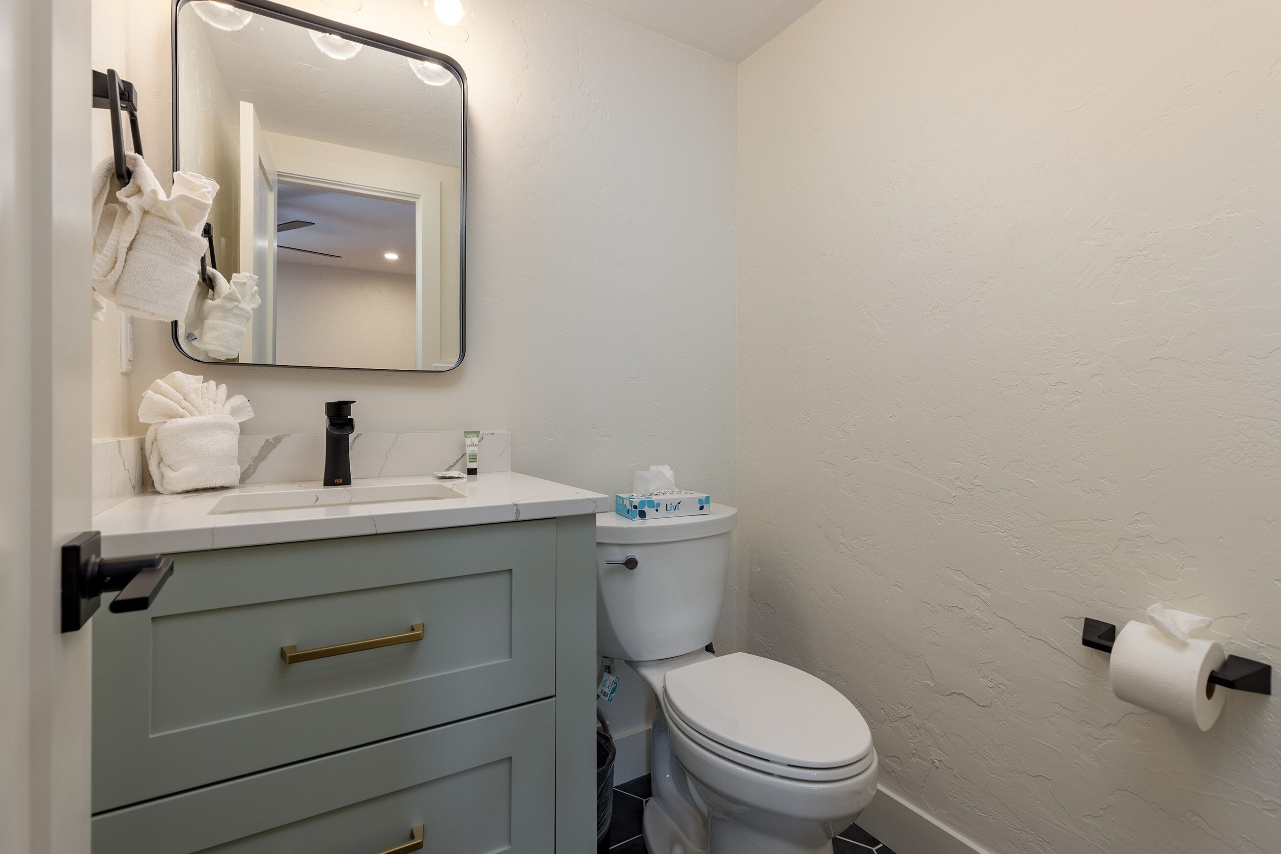 A bathroom with a white sink, a mirror, a toilet, and a towel rack.