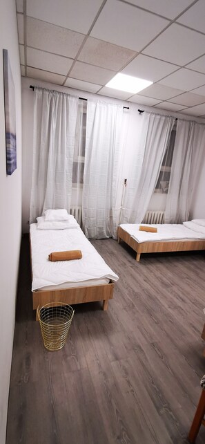 A room with two wooden beds, white bedding, and a woven basket. - Hostel Warszawa Powstaniec (Warsaw)