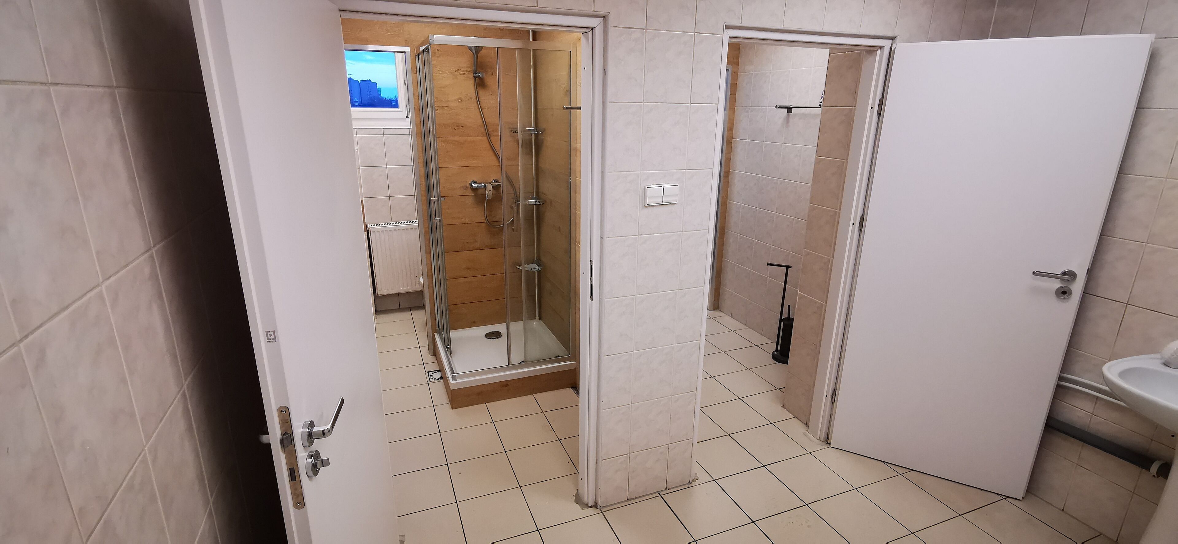 A bathroom with a glass-enclosed shower, a white sink, and a tiled floor.