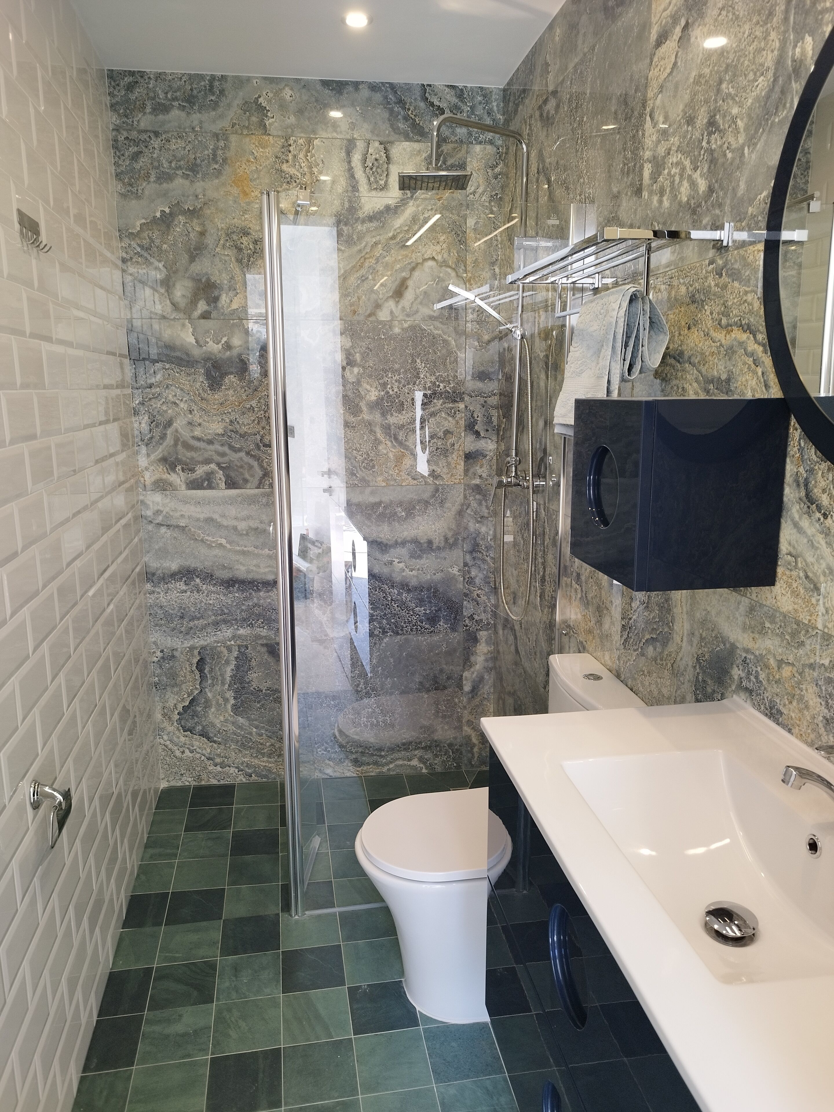 A modern bathroom with a glass shower enclosure, a white toilet, and a white sink with a black countertop.