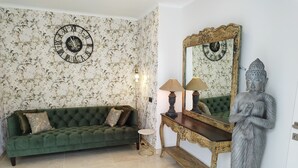 A room with a green sofa, a wooden console table with lamps, a large mirror, and a Buddha statue. - Modern luxury new build villa paradise, sea view, aircon, pool (Calpe)