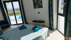 A bedroom with a bed, a bench, and a view of the outdoors. - Modern luxury new build villa paradise, sea view, aircon, pool (Calpe)