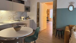 Une cuisine moderne dotée d’un plan de travail en marbre, un coin repas avec une table ronde et des chaises, et un salon avec un canapé et une table basse.