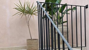 A staircase with a metal railing, a potted plant, and a textured basket on the landing. - RUA 39 fine apartments 4 (Syracuse)