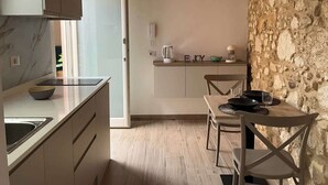 A modern kitchen with a marble countertop, wooden cabinets, and a stone wall. - RUA 39 fine apartments 4 (Syracuse)