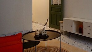 Une petite pièce avec une table ronde, une chaise rouge, un meuble blanc et une porte verte.
