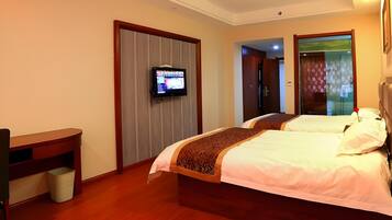 A hotel room with two beds, a television, a desk, and a trash bin.