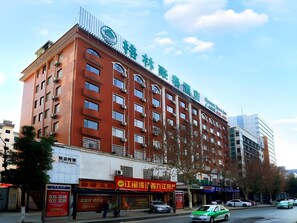 Un hotel de varios pisos con fachada roja, múltiples balcones y un letrero que indica que es un hotel.