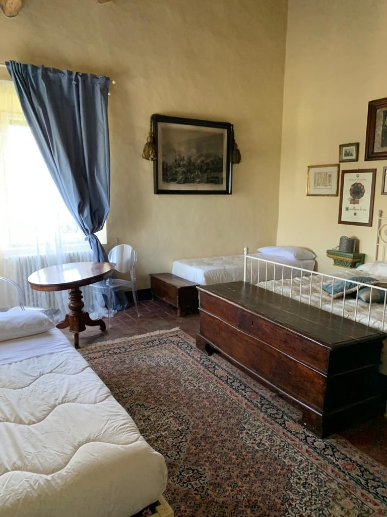 Una habitación con una cama, una mesita, una silla, un banco y una alfombra.