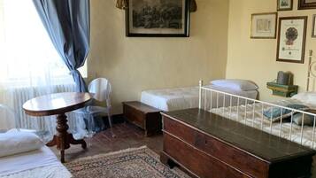 Una habitación con una cama, una mesita, una silla, un banco y una alfombra.