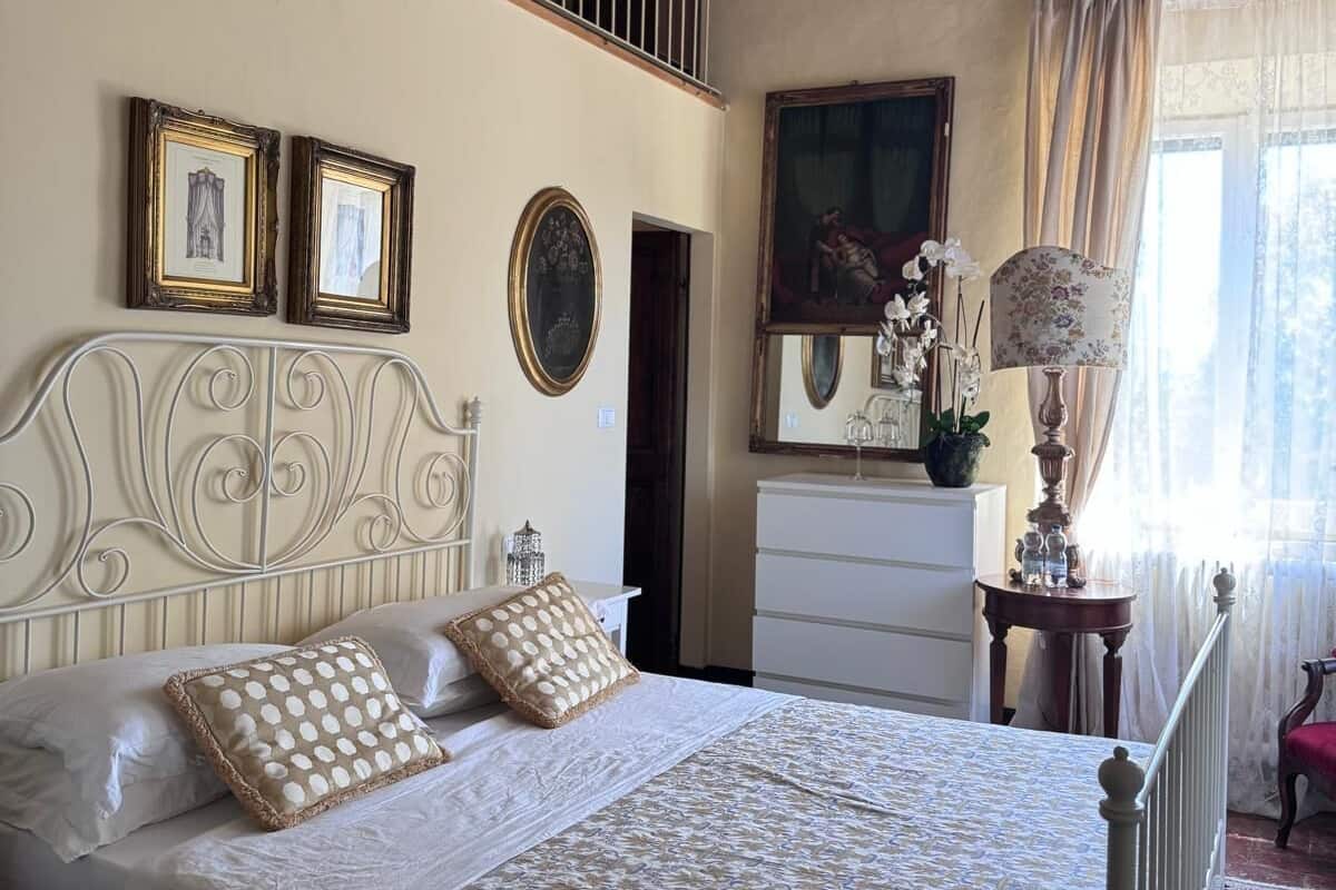 A bedroom with a bed, a dresser, a mirror, and a window with curtains.