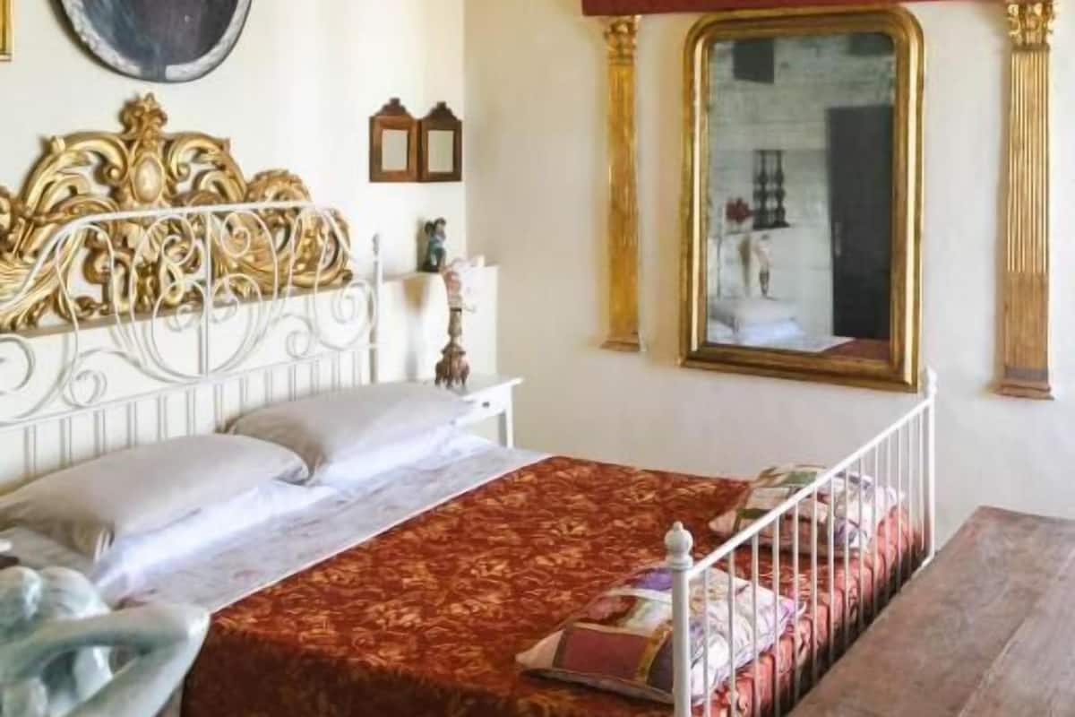 A bedroom with a bed, a nightstand, a dresser, a mirror, and a decorative headboard.
