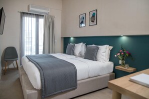Ein modernes Hotelzimmer mit einem Bett, einem Sessel, einem Schreibtisch und einer Wandklimaanlage.