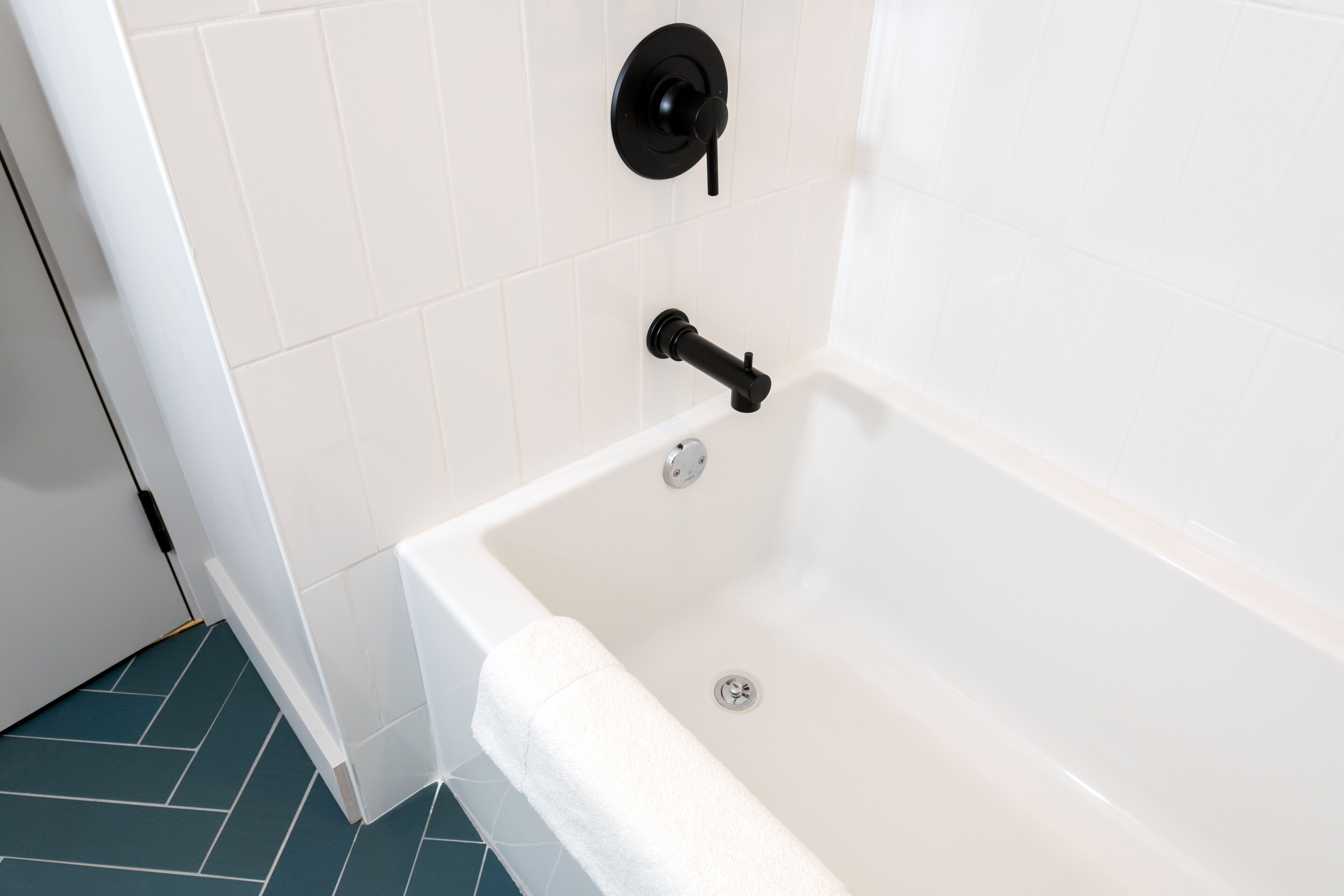 Un baño moderno con una bañera blanca, un grifo negro y una toalla blanca en el borde.