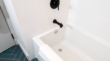 Un baño moderno con una bañera blanca, un grifo negro y una toalla blanca en el borde.
