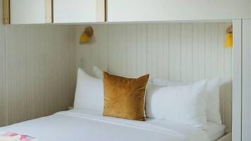 A bunk bed with a wooden ladder, white bedding, and a colorful quilt.