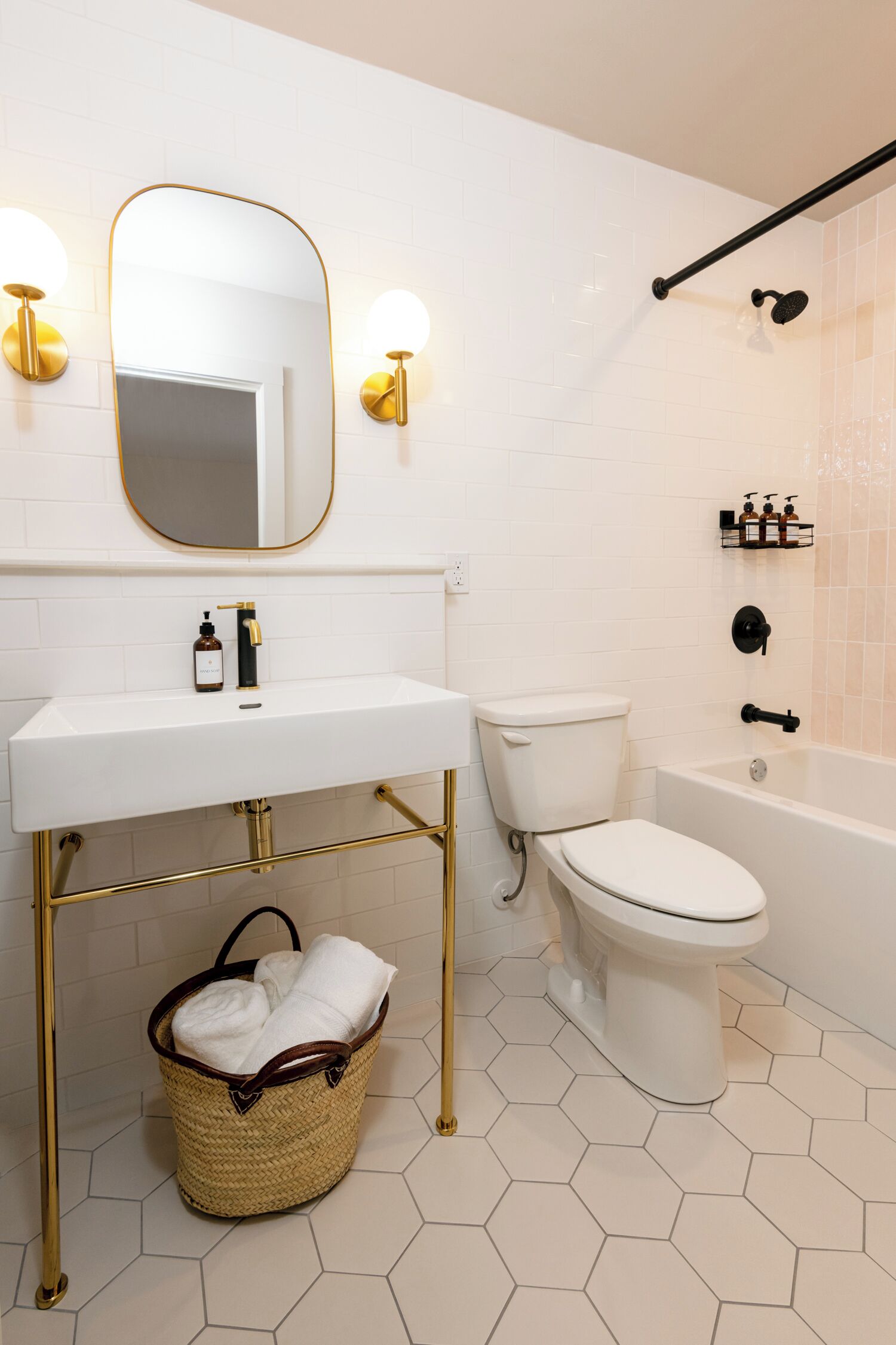 Casa de banho com lavatório branco, detalhes dourados, sanita e banheira.