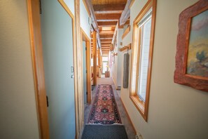 A hallway with wooden beams, a patterned carpet, and a framed picture on the wall.