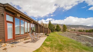 A building with large windows, a patio with chairs, and a view of mountains. - Homestead 2024 (Keystone)