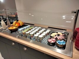 Un buffet proposant une variété d’aliments, notamment des yaourts, des fruits et des viandes.