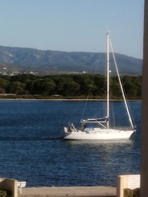 A sailboat on a calm body of water with a mountainous landscape in the background.