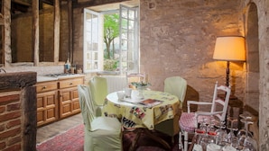 A rustic dining area with a stone wall, wooden beams, and a table set for two. - Beautiful Périgourdine house with pool access Hôtel La Roseraie (Montignac-Lascaux)