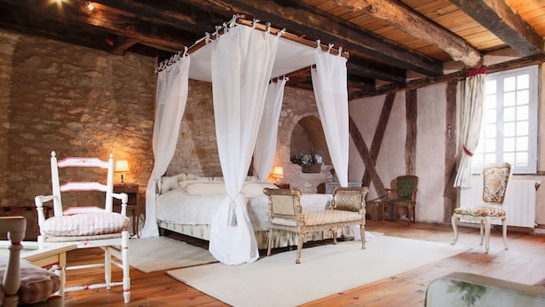 A rustic bedroom with a four-poster bed, a stone wall, wooden beams, and vintage furniture. - Beautiful Périgourdine house with pool access Hôtel La Roseraie (Montignac-Lascaux)