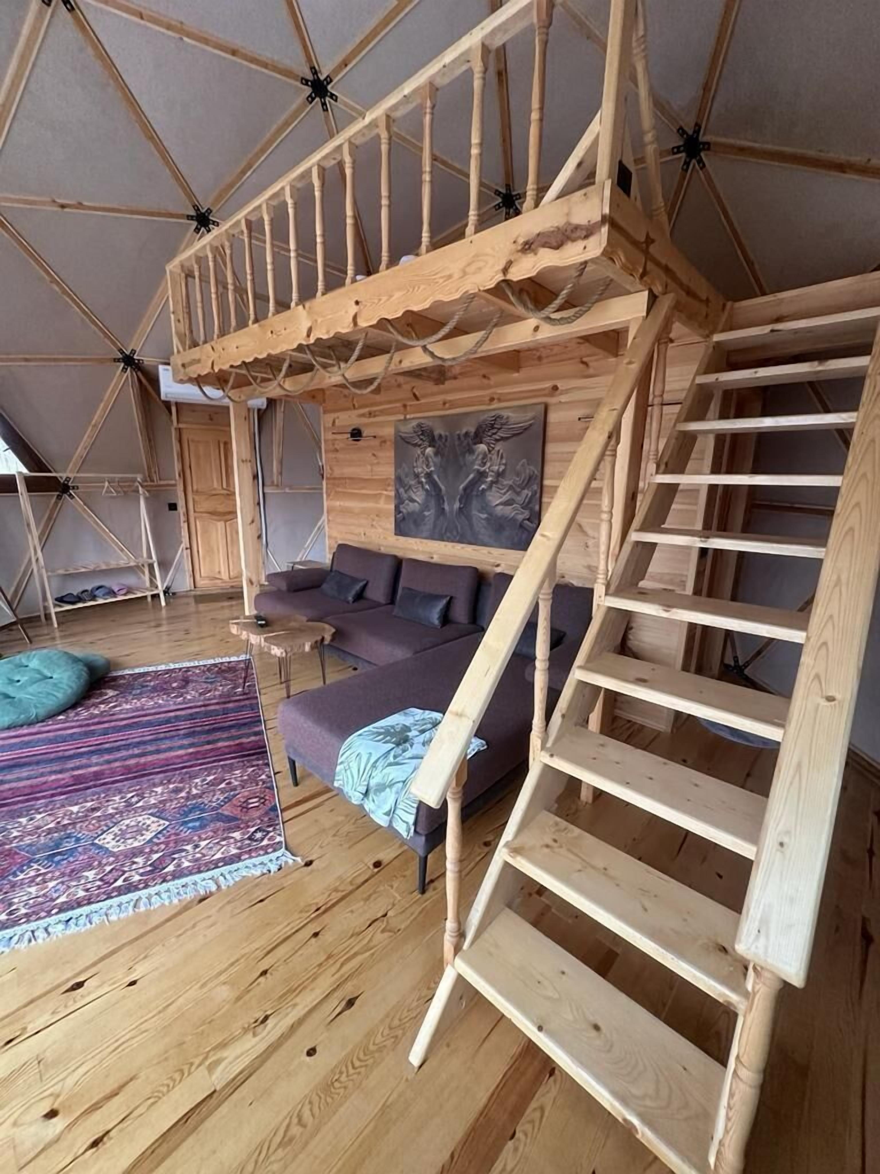 Un interior de madera con una escalera, un sofá y una alfombra.