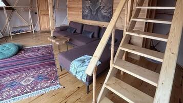 Un interior de madera con una escalera, un sofá y una alfombra.