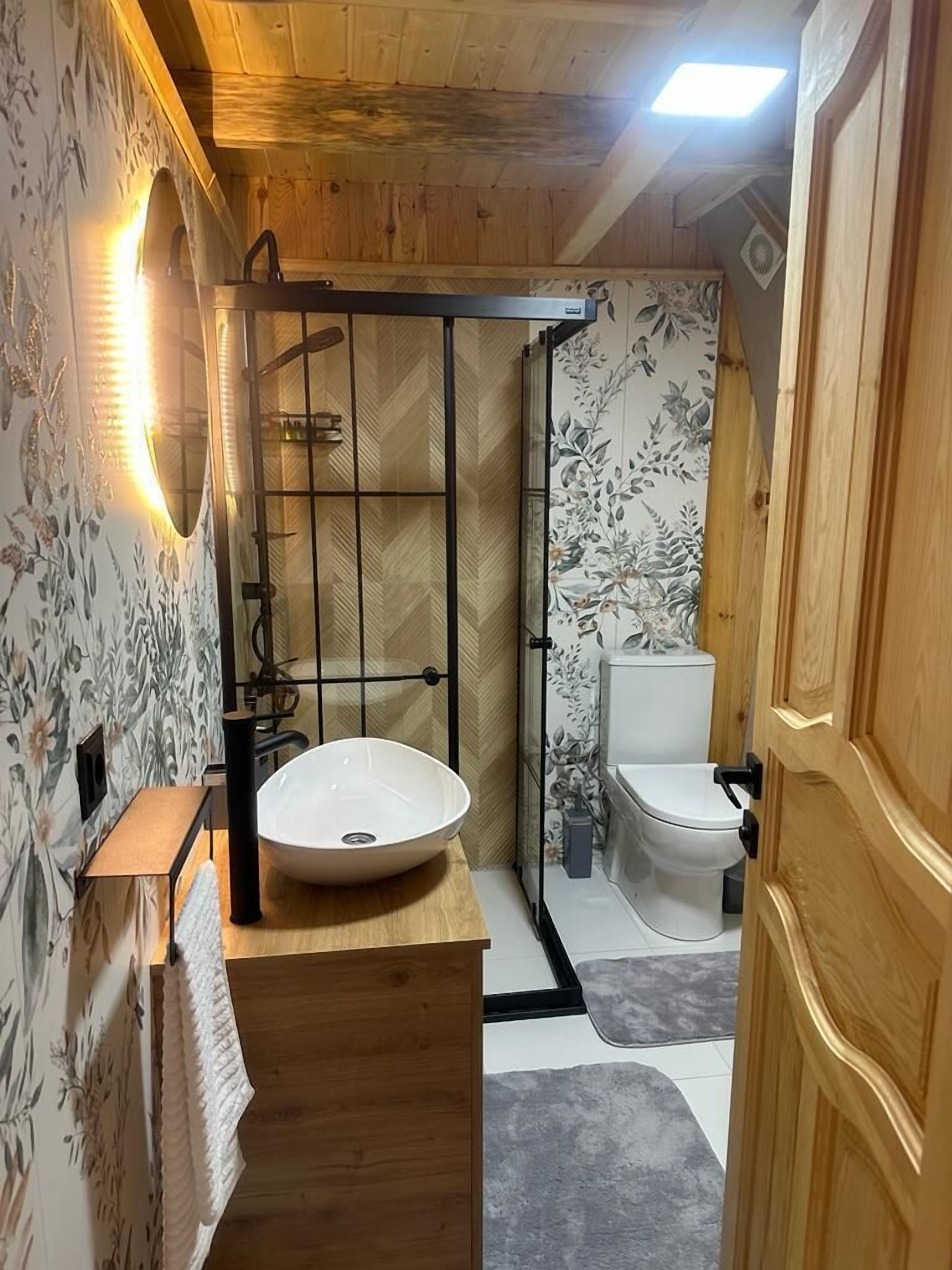 Un baño de madera con un lavabo grande, ducha e inodoro.
