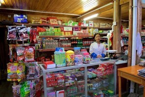 A store with shelves stocked with various packaged goods and a counter with a person behind it.