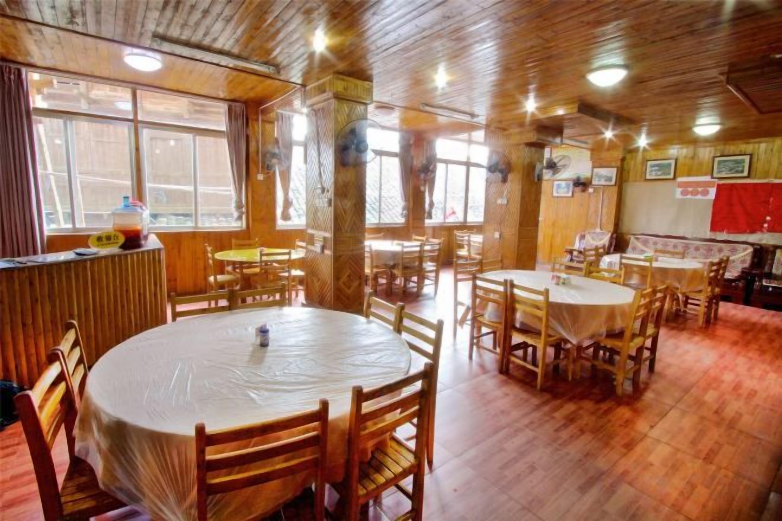 A dining area with round tables and chairs, wooden floors, and a bar counter.