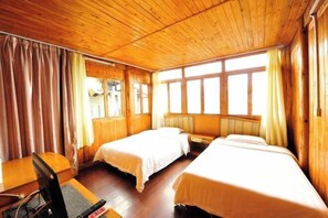 Una habitación de cabaña de madera con dos camas, un escritorio y una computadora.