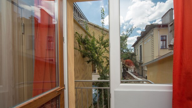 Un balcon donnant sur un arbre et des immeubles.