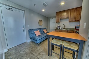 A compact kitchen with a dining area, a sofa, and a door. - Ocean Breeze (Panama City Beach)
