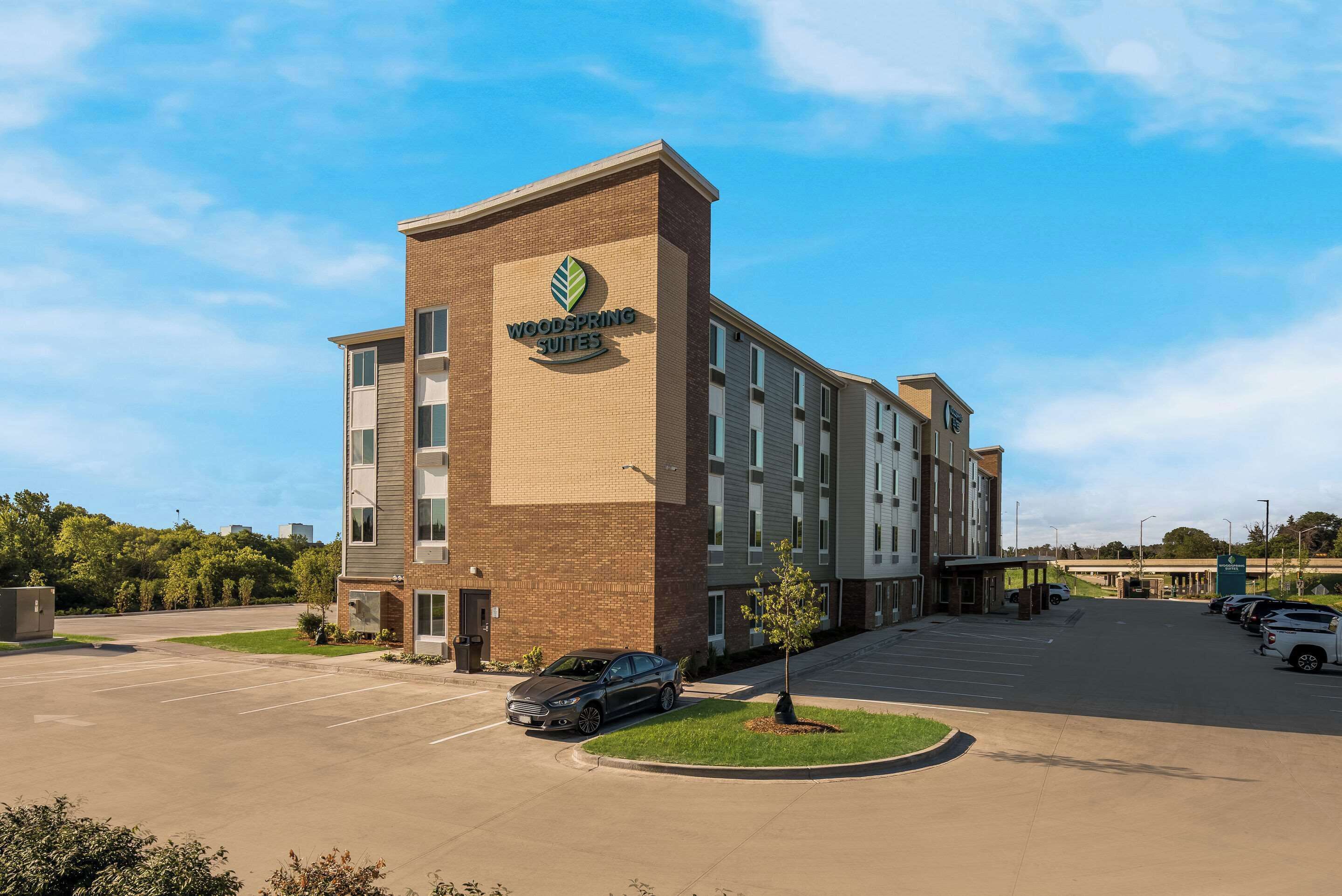 A hotel with a brick facade, a parking lot, and a clear sky.