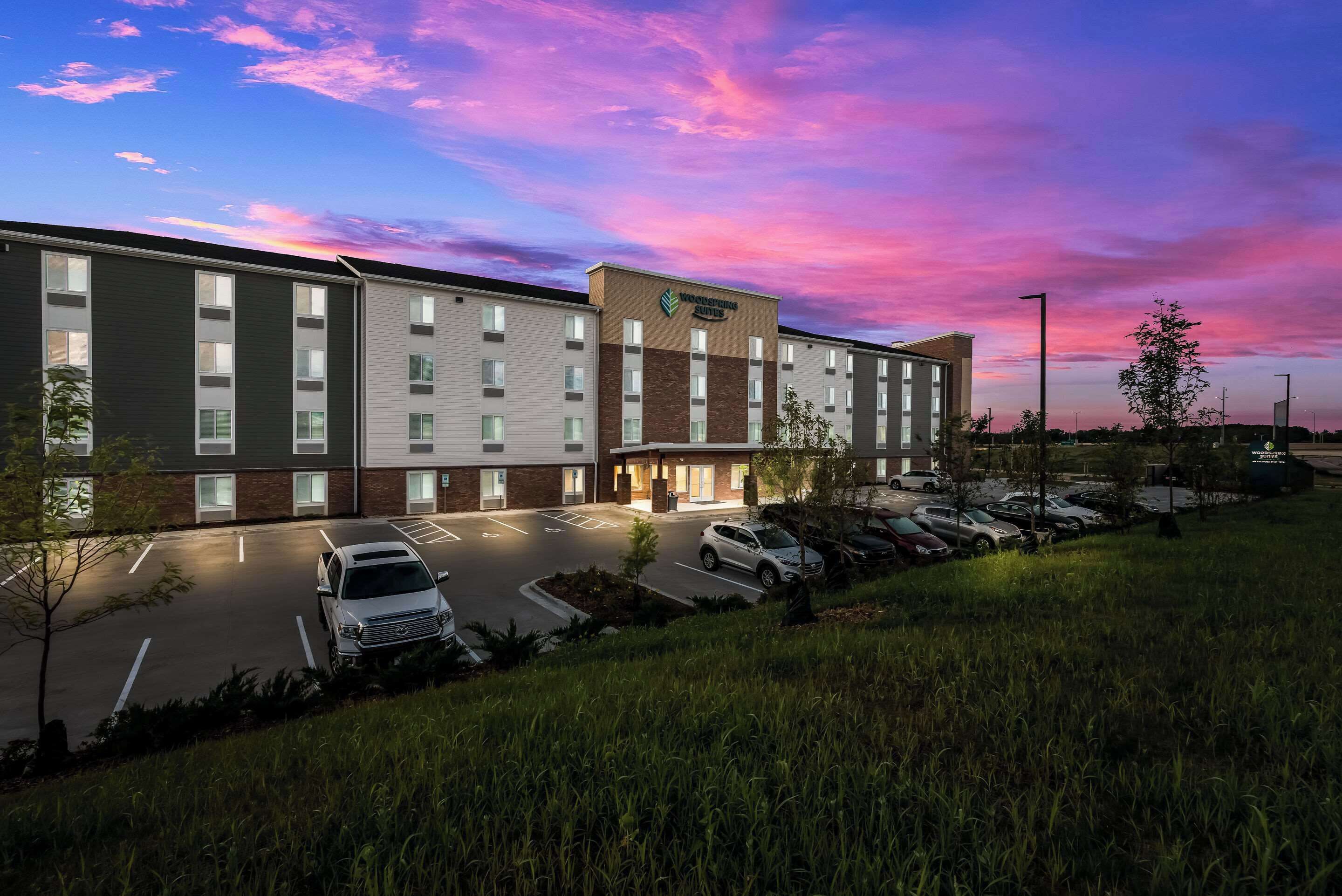 A modern hotel with a brick facade, multiple parking spaces, and a well-lit entrance.