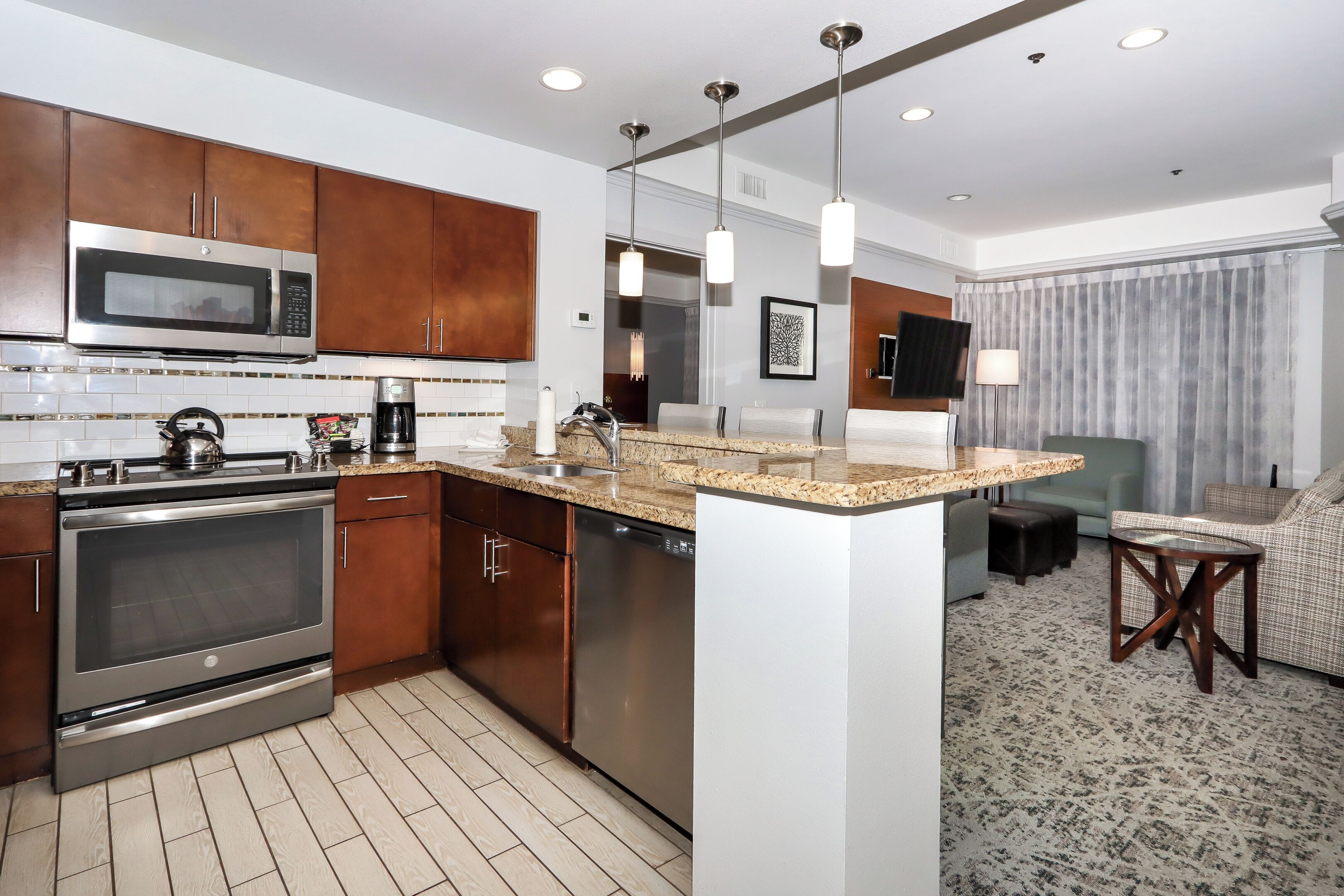 A modern kitchen with stainless steel appliances, a granite countertop, and a dining area with a sofa and table.