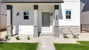 Ein zweistöckiges Haus mit weißer Fassade, einer Veranda und einer Garage.