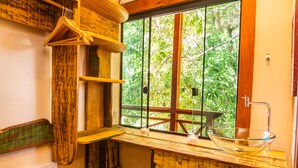 Eine rustikale Küche mit Holzböden, einem Spülbecken aus Glas und einem Fenster mit Blick auf Grünflächen.