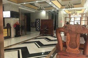A lobby with a black and white patterned floor, a wooden reception desk, and a chandelier. - Wangxinge Hotel (Nan County)