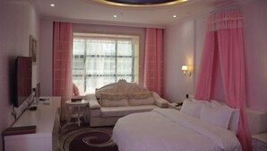 A hotel room with a large bed, a sofa, a desk, and a television. - Wangxinge Hotel (Nan County)