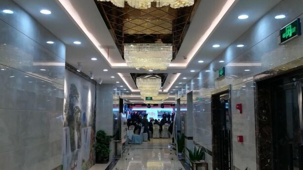 A hotel corridor with a polished marble floor, a chandelier, and a mural on the wall. - Wangxinge Hotel (Nan County)