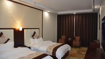A hotel room with two beds, a TV, a small table, and a chair.